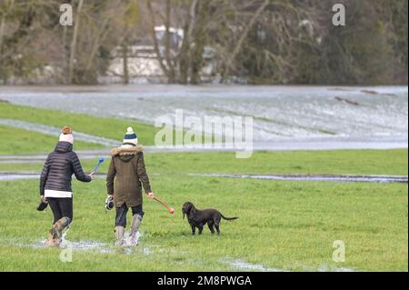 Upton Upon Severn, Worcestershire, 15. Januar 2023 – die Stadt Upton-upon-Severn ist fast abgeschnitten, mit nur einer Straße in und einer Straße, nachdem der Fluss Severn begonnen hatte, über erhöhte Flussufer zu fließen und die umliegenden Felder zu überschwemmen. Eine Tankstelle und ein lokaler Morrisons Supermarkt waren zu einer Insel aus der Flut geworden. Zwei Spaziergänger wurden auf einem Bauernfeld gesehen, wie sie ihren Weg durch flaches Wasser machten, während sie mit ihrem Hund gingen. Quelle: Stop Press Media/Alamy Live News Stockfoto