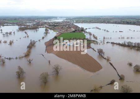 Upton Upon Severn, Worcestershire, 15. Januar 2023 – die Stadt Upton-upon-Severn ist fast abgeschnitten, mit nur einer Straße in und einer Straße, nachdem der Fluss Severn begonnen hatte, über erhöhte Flussufer zu fließen und die umliegenden Felder zu überschwemmen. Eine Tankstelle und ein lokaler Morrisons Supermarkt waren zu einer Insel aus der Flut geworden. Zwei Spaziergänger wurden auf einem Bauernfeld gesehen, wie sie ihren Weg durch flaches Wasser machten, während sie mit ihrem Hund gingen. Quelle: Stop Press Media/Alamy Live News Stockfoto