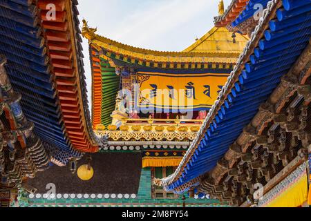 Farbenfrohe Dächer mit Balken und Ornamenten und spektakuläre Dekorationen in einem Tempel im Kumbum Jampaling Kloster, Xining, China Stockfoto