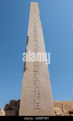Hieroglypische Schnitzereien auf der hohen Obelisk-Säule am alten ägyptischen Karnak-Tempel in Luxor Ägypten vor blauem Himmel Stockfoto