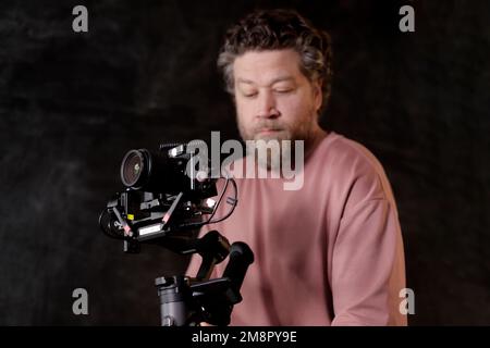 ein weißer Mann, der Gimbal mit Kamera in der Nahaufnahme hält Stockfoto