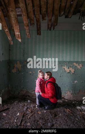 Mutter und Tochter in zerstörtem Gebäude. Krieg, Flüchtlinge, Kriegskrisenkonzept. Stockfoto