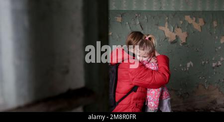 Mutter und Tochter in zerstörtem Gebäude. Krieg, Flüchtlinge, Kriegskrisenkonzept. Stockfoto