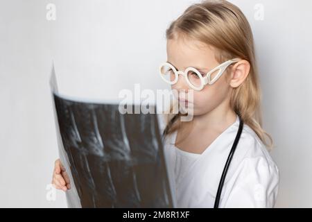 Arzt mit Brille und Stethoskop, sieht ernst aus und hält Röntgenfilm, CT-Scan, MRT der Wirbelsäule. Neurologe bei der Arbeit. Neutrale Ba Stockfoto