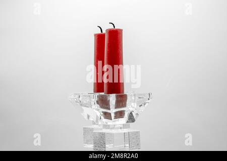 Nahaufnahme von zwei roten Kerzen in durchsichtigen, glasgeformten Kerzenhaltern Stockfoto