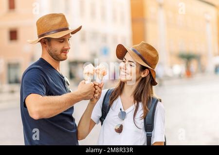 Glückliches Paar, das in Rom, Italien, Eis isst. Wunderschönes, helles Eis mit verschiedenen Geschmacksrichtungen in den Händen eines Paares Stockfoto