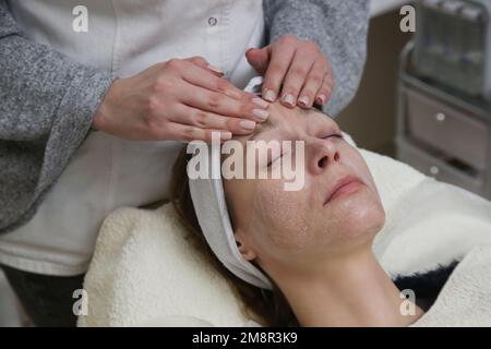 Dermatologe bereitet die Gesichtshaut der Frau für die Behandlung vor. Reinigungs-, Peeling- und Peeling-Prozess. Stockfoto