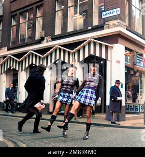 Ein Mann und eine Frau, die sich in identischen Outfits aus Pullover und Rock in der modischen Carnaby Street, London 1968, posieren. Nach der Produktion gefärbt. Foto von Tony Henshaw Archive Stockfoto