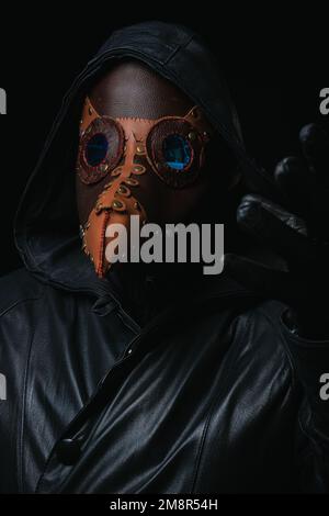 Pestdoktor mit Krähenartige Maske isoliert auf schwarzem Hintergrund gruselig halloween historisch schreckliche Kostüm Konzept Epidemie Covid Pocken Affen Stockfoto