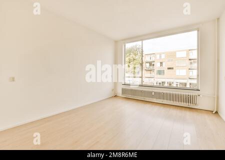 Ein leerer Raum mit weißen Wänden und Hartholzböden, es gibt ein großes Fenster im Zimmer ohne Fenster Stockfoto