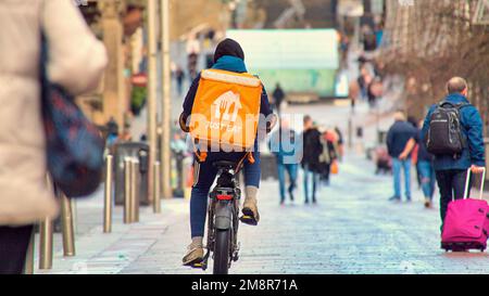 Glasgow, Schottland, Vereinigtes Königreich 15. Januar 2023. UK Weather: Eat einfach nur Lieferung Radfahrer nass und windig sah nasse, elende Straßen als es diese Woche herauskam die Lebenserwartung für Einheimische war mit 74 die niedrigste in großbritannien. Ungesunde Ernährung ist das Bild der Stadt mit Lieferrädern, die die Style Meile der Buchannan Straße befallen. Credit Gerard Ferry/Alamy Live News Stockfoto