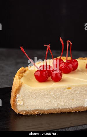 Klassischer Käsekuchen mit Kirschen auf dunklem Hintergrund. Stockfoto