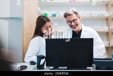 Glückliche Apotheker-Video, einen Patienten am Computer in einer Apotheke anzurufen. Reife Gesundheitsdienstleister, die Online-Rezepte in einer Apotheke verarbeiten. Stockfoto