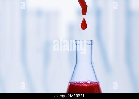 Ein Tropfen Blut. Pipette. Medizinkolben mit roter Flüssigkeit. Blutflasche. Tropfende rote Flüssigkeit. Ein Tropfen Rot. Tests, Blutgruppe. Stockfoto