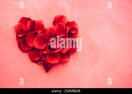 Herz aus Rosenblättern auf pinkfarbenem Hintergrund. Valentinstag Stockfoto