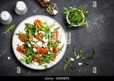 Rucola Salat mit Tomaten, Blauschimmelkäse und Walnüssen. Gesundes vegetarisches Gericht. Bild von oben. Stockfoto