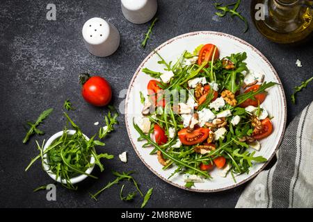 Rucola-Salat mit Tomaten, Blauschimmelkäse und Walnüssen. Gesundes vegetarisches Gericht. Draufsicht, Nahaufnahme. Stockfoto