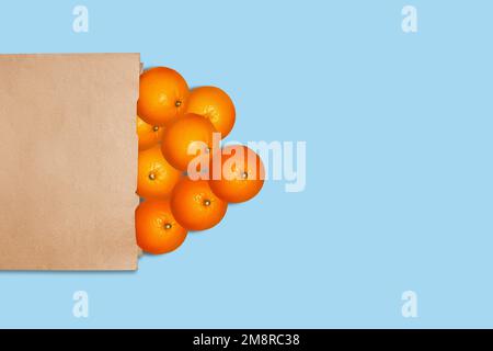Orangen in einer Papiertüte. Auf blauem Hintergrund. Stockfoto