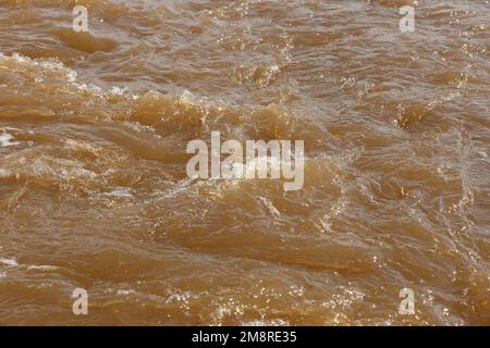 Schlammiges Flusswasser. Quellfluss mit braunem schlammigem Wasser. Hintergrund Stockfoto