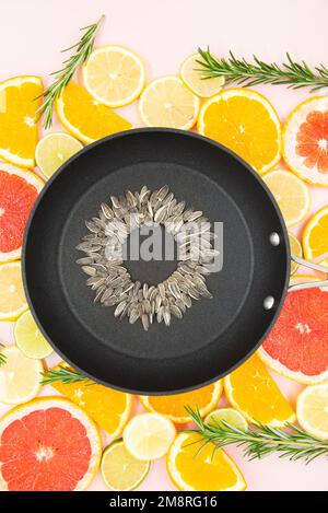 Hintergrund der Scheiben von Zitrusfrüchten, Orangen, Zitronen, Limetten, Grapefruits, Auf dem eine schwarze Pfanne platziert wird, in der eine Sonnenblume hergestellt wird Stockfoto