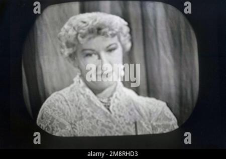 1957, historisch, die Schauspielerin Barbara Kelly auf BBC Television, die in der britischen Spielshow "What's My Line?" erscheint. Die von 1951 bis 1963 auf dem BBC-Fernsehen ausgestrahlte Spielshow basiert auf der US-Version des gleichen Namens und war eine der beliebtesten Fernsehsendungen der Epoche. Die Panelmitglieder der Show mussten die Teilnehmer befragen, um zu versuchen, ihren Beruf zu erraten, d. h. ihren „Beruf“. Barbara Kelly wurde in Vancover, Kanada, geboren und war eine der regulären Diskussionsteilnehmer der ursprünglichen BBC-Serie. Stockfoto