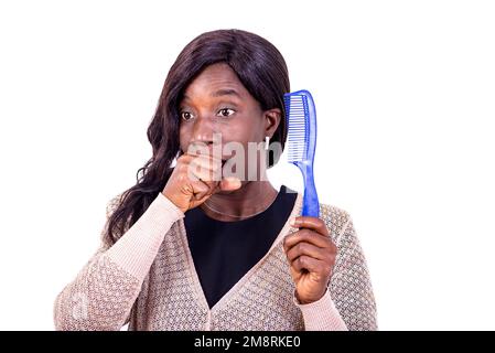 Porträt einer schönen, überraschten, reifen Frau, die einen Kamm hält und den Mund mit der Hand bedeckt. Stockfoto