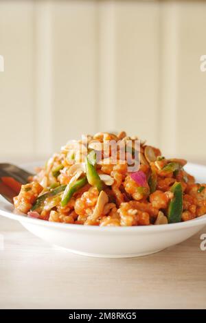 Salat mit frischem Gemüse und Nüssen in einer Schüssel auf dem Tisch Stockfoto