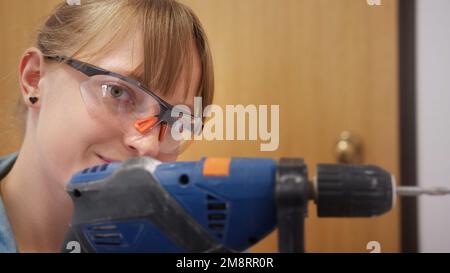 Nahgesicht einer Frau in Schutzbrille mit Bohrer zur Hausrenovierung. Hochwertiges Foto Stockfoto