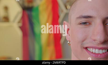 Halbgesicht eines lächelnden Kaukasiers mit LGBT-Flagge im Hintergrund. Hochwertiges Foto Stockfoto