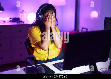 Eine junge, wunderschöne latina-Frau, die gestresst mit dem Computer im Spielzimmer spielte Stockfoto