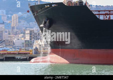 Großes, verankertes Frachtschiff, das Ballastwasser aus Anchors Hub ableitet. Stockfoto