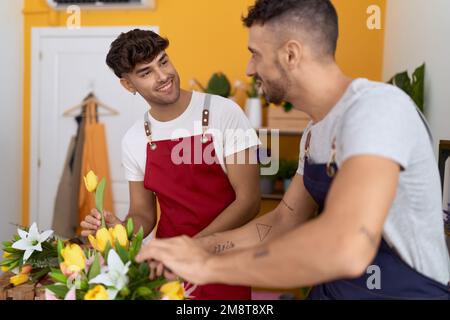 Zwei hispanische Blumenhändler, die selbstbewusst lächeln, machen einen Blumenstrauß im Blumenladen Stockfoto