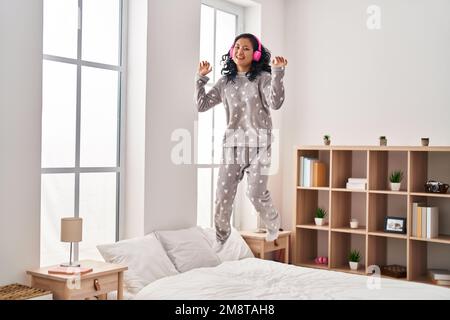 Junge chinesin hört Musik und tanzt im Schlafzimmer auf dem Bett Stockfoto