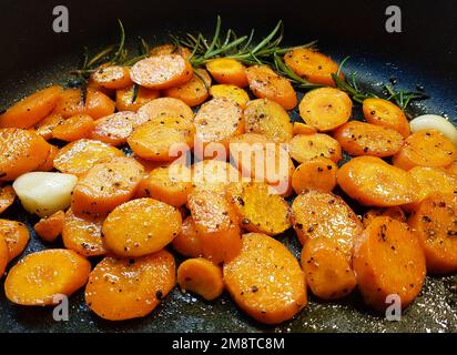 In Scheiben geschnittenes Wurzelgemüse und Knoblauch in einer Pfanne Stockfoto
