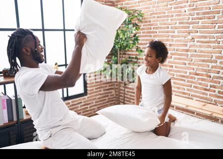 Vater und Tochter liegen auf dem Bett und streiten mit dem Kissen im Schlafzimmer Stockfoto