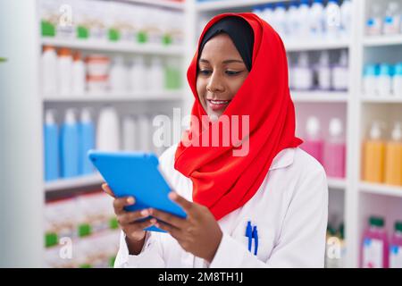 Junge, schöne Apothekerin, die Touchpad benutzt und in der Apotheke arbeitet Stockfoto