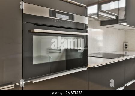 Eine moderne Küche mit schwarzen Schränken und Edelstahlgeräten auf den Arbeitsflächen, in diesem Fall ist es ein Ofen Stockfoto