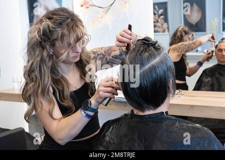 Der Friseur schneidet absichtlich die Haare eines älteren Mannes Stockfoto