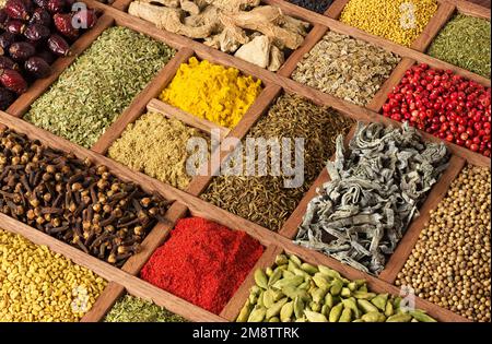 Gewürze und Kräuter in Holzkisten. Mehrfarbige Gewürze im Nahbereich als Hintergrund. Stockfoto