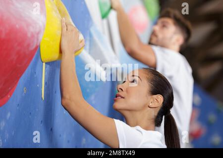 Junge Frau, die sich auf die Kletterwand einsetzt Stockfoto