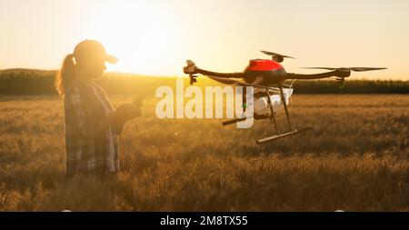 Frau Farmer kontrolliert die Drohnenspritze mit einer Tablette. Intelligente Landwirtschaft und präzise Landwirtschaft Stockfoto