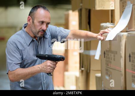 Mann, der Barcodescanner in einer Lagerfabrik handhabt Stockfoto