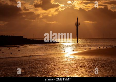 New Brighton, Großbritannien: Sonnenuntergang über der Liverpool Bay am Rand der Gezeiten, neben dem Navigationsmarkierungsposten und der Meeresabwehr. Stockfoto