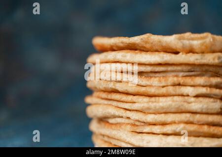 Fladenbrot Lavash, Chapati, Naan, ein Haufen Tortilla auf blauem Hintergrund hausgemachtes Fladenbrot gestapelt. Stockfoto