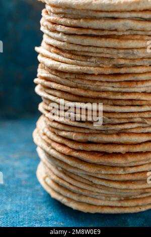 Fladenbrot Lavash, Chapati, Naan, ein Haufen Tortilla auf blauem Hintergrund hausgemachtes Fladenbrot gestapelt. Stockfoto