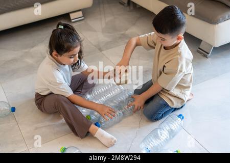 Kreative Ideen mit Plastikflaschen. Kinder stellen aus Plastikflaschen recycelten Spielzeugturm her. Kinder spielen mit Plastikflaschen. Stockfoto