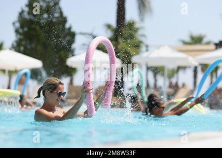 Glückliche Touristin mit Sonnenbrille, die am sonnigen Tag im Swimmingpool lächelt. Stockfoto