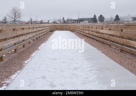 Gillette, Wyoming - 25. Januar 2021: Leichter Schneefall auf einem Wanderweg auf der Brücke im Dalbey Memorial Park in Gillette, Wyoming. Stockfoto