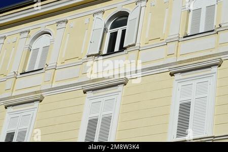 Ein offenes Fenster auf dem Dach eines gelben Gebäudes im Jugendstil Stockfoto