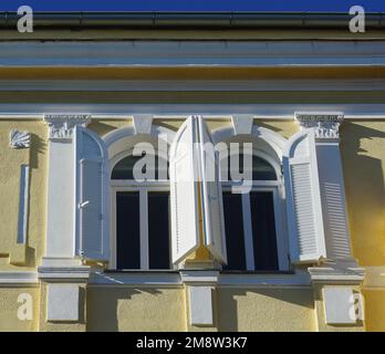 Halbkreisförmige Jugendstilfenster auf der gelb bemalten Fassade des Gebäudes Stockfoto